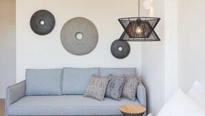 Ein modernes Wohnzimmer mit grauem Sofa, gemusterten Kissen und Wandbildern.