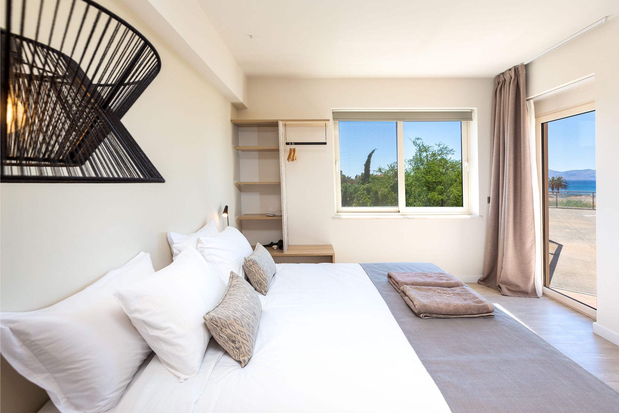 Quarto com cama grande, guarda-roupa, janela com vista e luminária no teto.