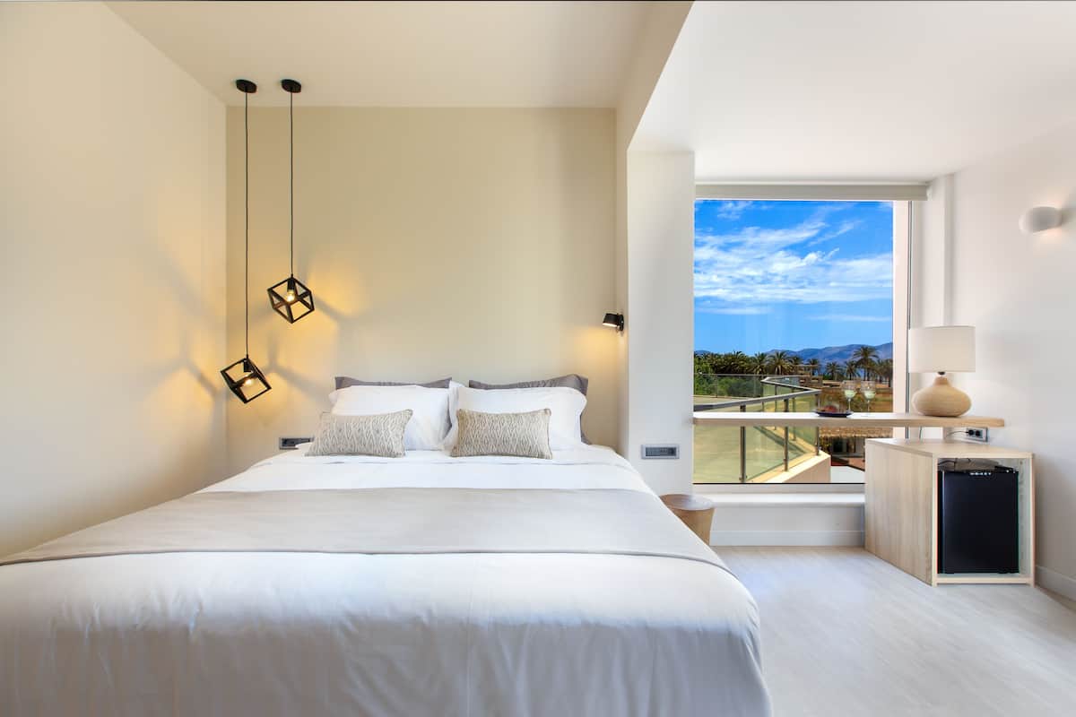 Une chambre moderne avec un grand lit, une vue sur l’extérieur et une petite kitchenette.