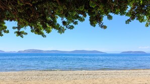 Ein Strand mit freiem Blick auf das Meer und ferne Berge.