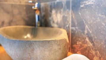 A stone basin with a faucet in a bathroom with marble walls.