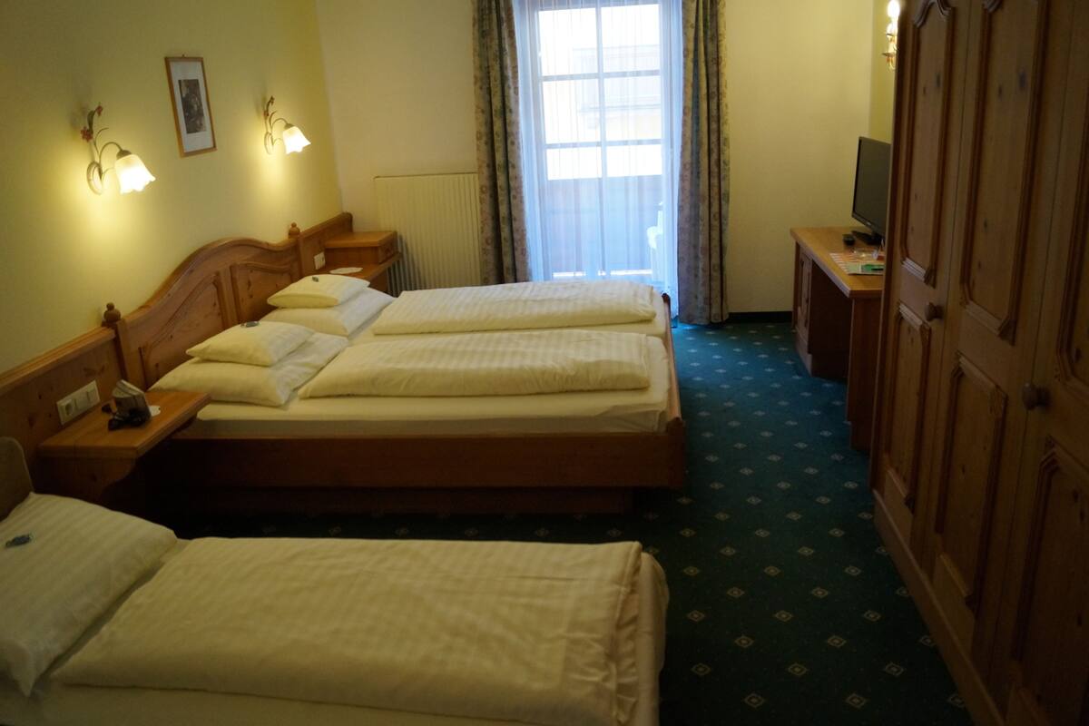A hotel room with two beds, a desk with a computer, and a wardrobe.