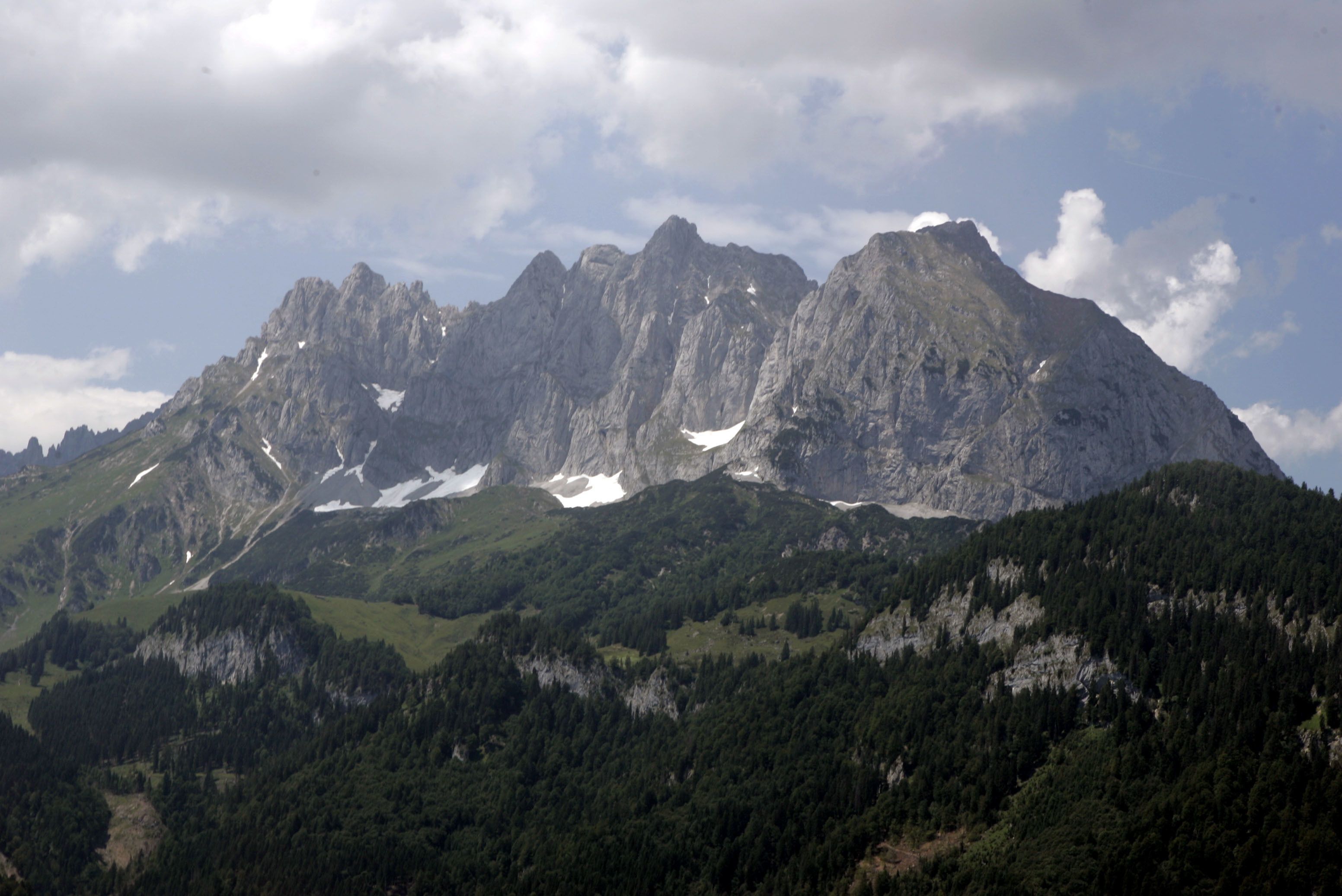 A mountain landscape with rugged peaks and dense forest.