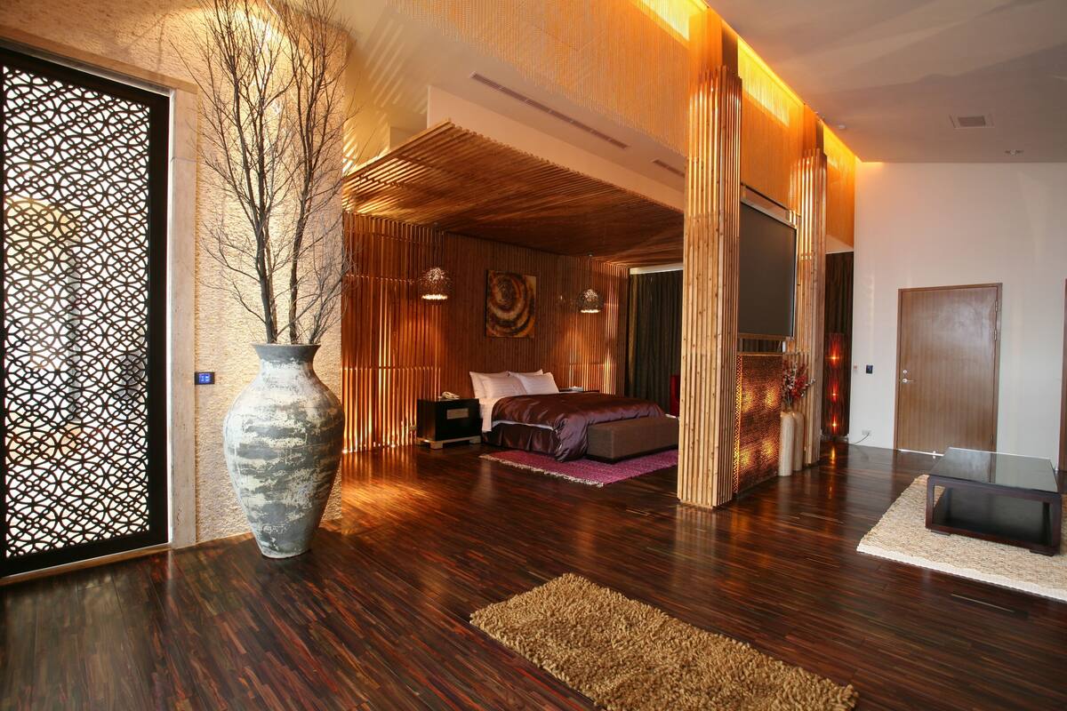 Un dormitorio moderno con una cama grande, una mesita de noche, un florero y un techo de madera.
