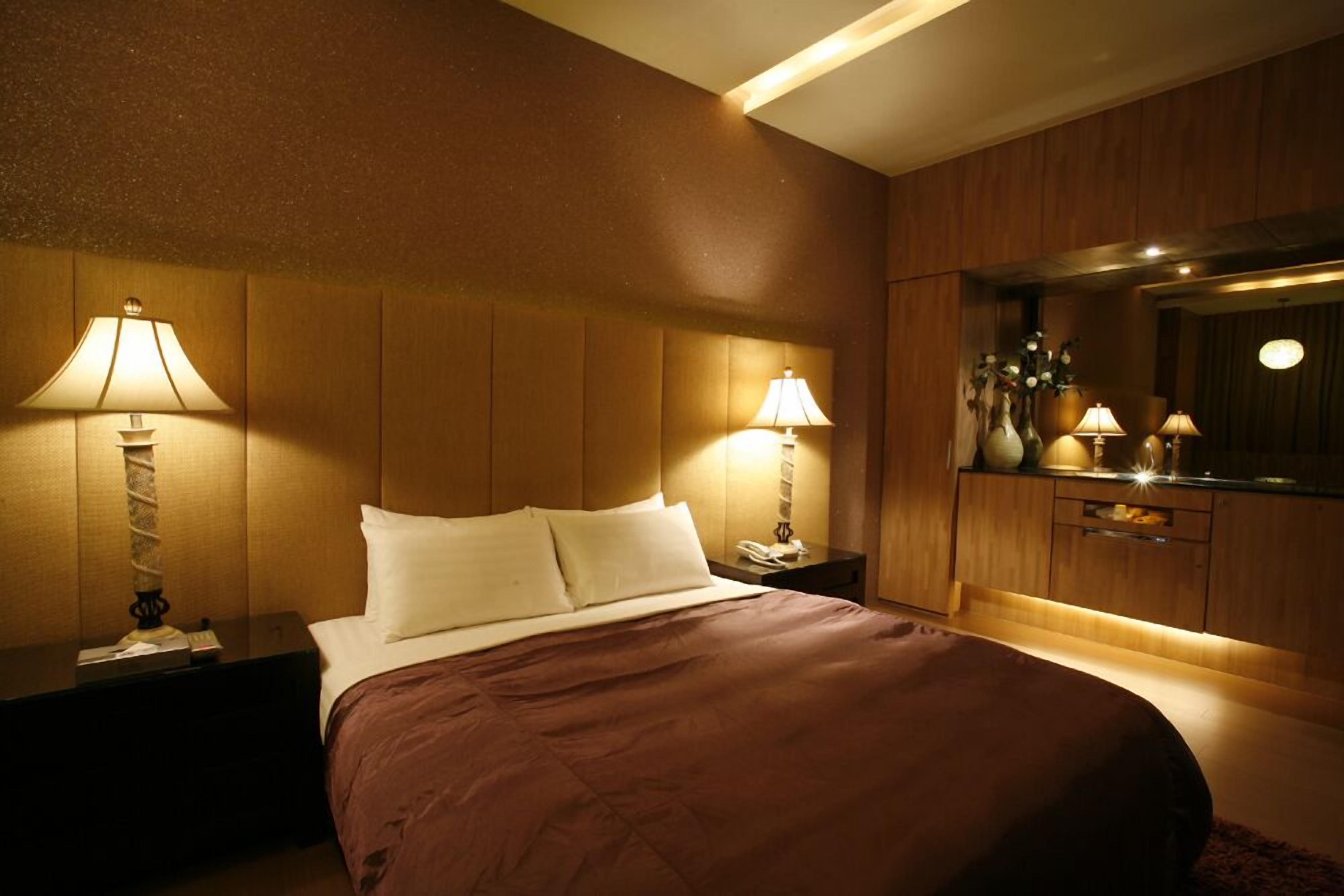 Een hotelkamer met een groot bed, twee bedlampen, een nachtkastje, een dressoir en een spiegel.