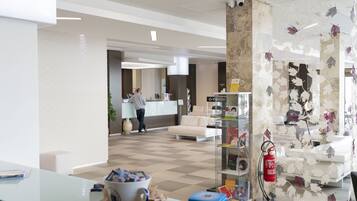 A modern hotel lobby with a reception desk, seating area, and a fire extinguisher.