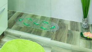 A modern bathroom with a washing machine, a toilet, and a decorative mat on the floor.