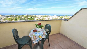 A balcony with two chairs, a table with a tablecloth, and a vase with flowers. - Hotel Terme Tramonto d'oro (Forio)