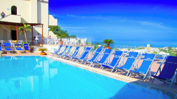 A pool area with blue lounge chairs and a clear view of the sea. - Hotel Terme Tramonto d'oro (Forio)