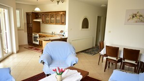 Un vaste salon comprenant un coin repas, une cuisine et offrant une vue sur l’extérieur.