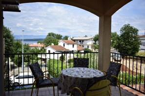 A balcony with a table and chairs, overlooking a residential area with houses and a road. - Apartment Diana (Malinska-Dubasnica)