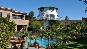 Uma casa moderna com piscina, rodeada por vegetação exuberante e palmeiras.