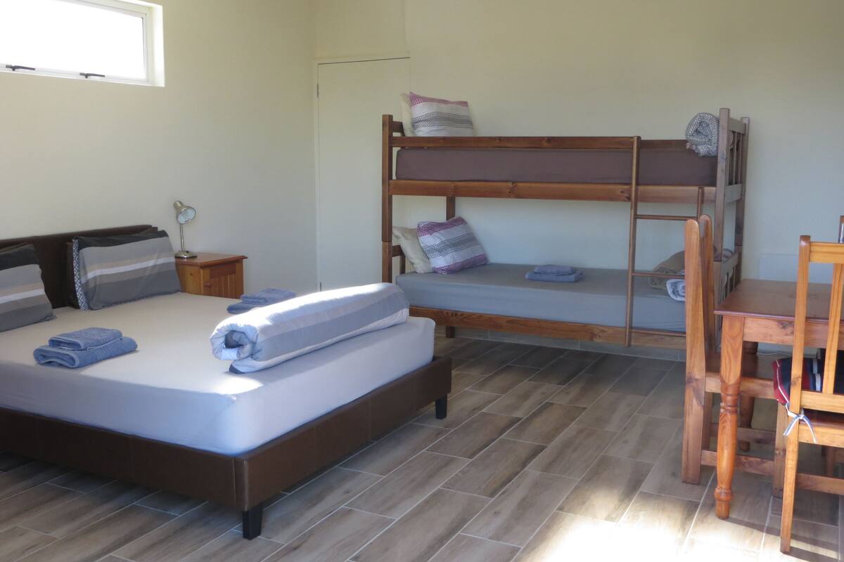 A bedroom with a bunk bed, a single bed, a desk, and a chair.