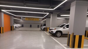 A parking garage with multiple parking spaces, a sign for Brown-Dot Hotel, and a white SUV parked in one of the spaces. - Browndot Hotel Gwangju Hanam Branch (Gwangju)