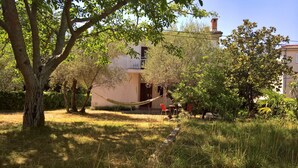 A house with a balcony, surrounded by trees and a hammock. - Apartment Dory (Malinska-Dubasnica)