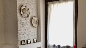 A room with a stone fireplace, a door with a curtain, and a small table with a television. - Lovely studio apartment within walking distance of the center of Chiesa Valmalenco (Chiesa in Valmalenco)