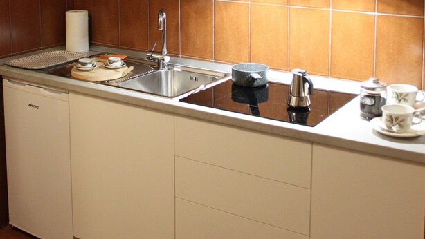 A kitchen with white cabinets, a stainless steel sink, a coffee maker, and a roll of paper towels. - Lovely studio apartment within walking distance of the center of Chiesa Valmalenco (Chiesa in Valmalenco)