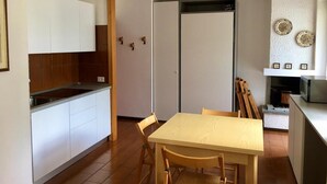 A compact kitchen with white cabinets, a wooden dining table, and a microwave. - Lovely studio apartment within walking distance of the center of Chiesa Valmalenco (Chiesa in Valmalenco)