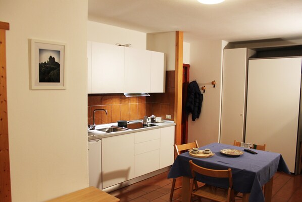 A compact kitchen with white cabinets, a sink, and a dining area with a table set for two.