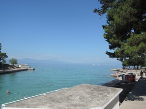 Vista costera con mar azul cristalino, un muelle y algunas embarcaciones.