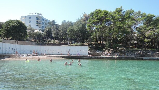 A swimming pool area with clear water, surrounded by trees and a hotel named 'Hotel Malen' in the background. - Apartment Dubravka (Malinska-Dubasnica)