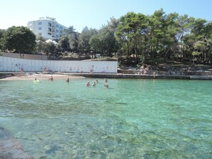 A swimming pool area with clear water, surrounded by trees and a hotel named 'Hotel Malen' in the background. - Apartment Dubravka (Malinska-Dubasnica)