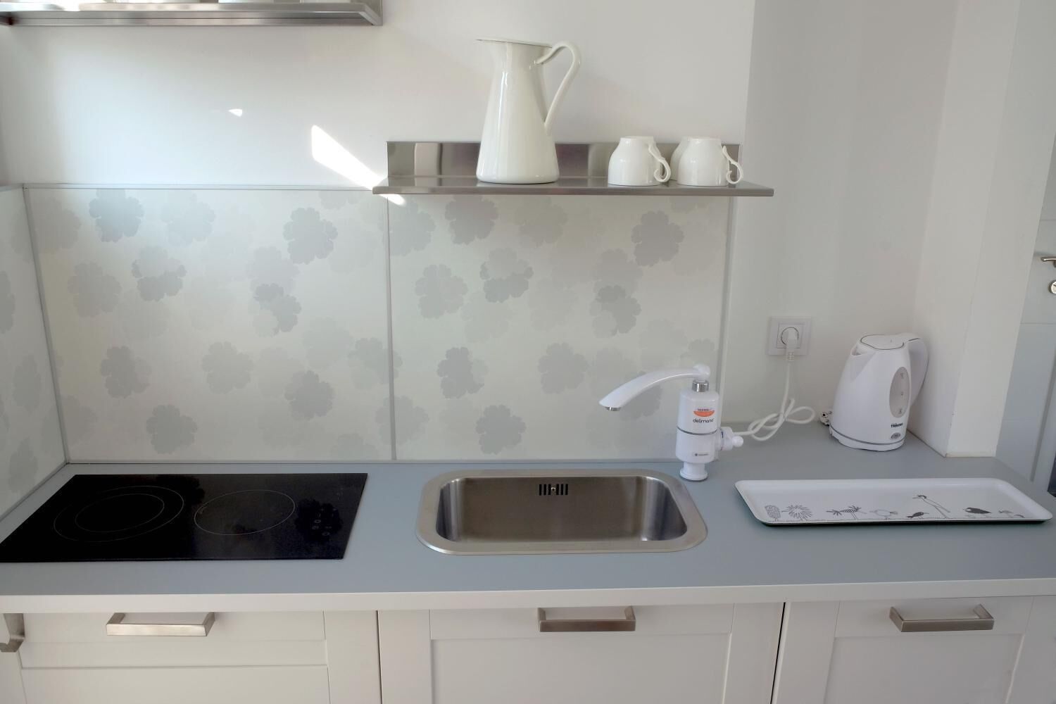 A modern kitchen with a stainless steel sink, a kettle, and a coffee maker.