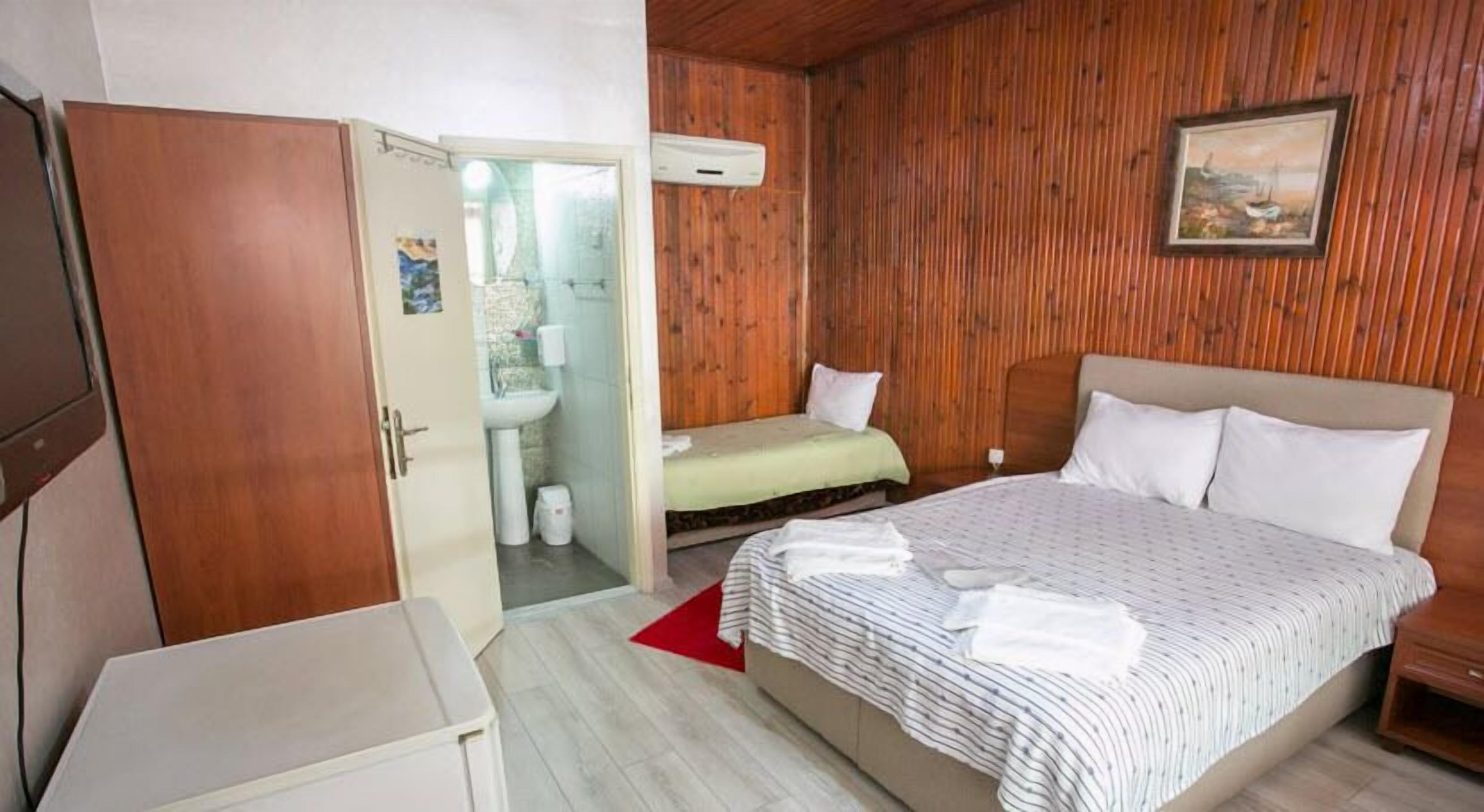 Un dormitorio con cama, mesita de noche, armario y baño visible a través de una puerta abierta.