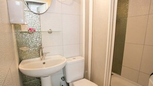 A bathroom with a white sink, toilet, and a shower area. - Carsi Pansiyon (Amasra)