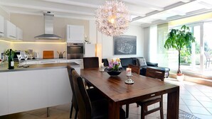 Una cucina moderna con mobili bianchi, un'isola centrale e un'area pranzo con tavolo e sedie in legno.