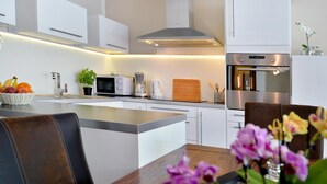 Una cucina moderna con mobili bianchi, un'isola centrale ed elettrodomestici in acciaio inossidabile.