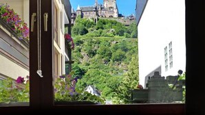 Una stanza con un letto, una finestra e vista su un castello su una collina.