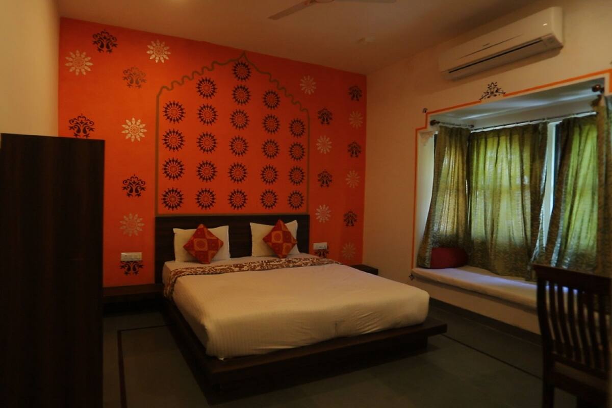 A bedroom with a bed, a window with curtains, and a wall with a pattern.