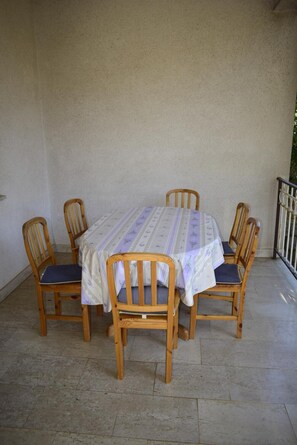 Una mesa redonda de madera con mantel floral, rodeada por seis sillas de madera con cojines.