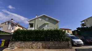 A two-story building with a stone wall and a metal fence in front. - Apartment Gloria (Dobrinj)