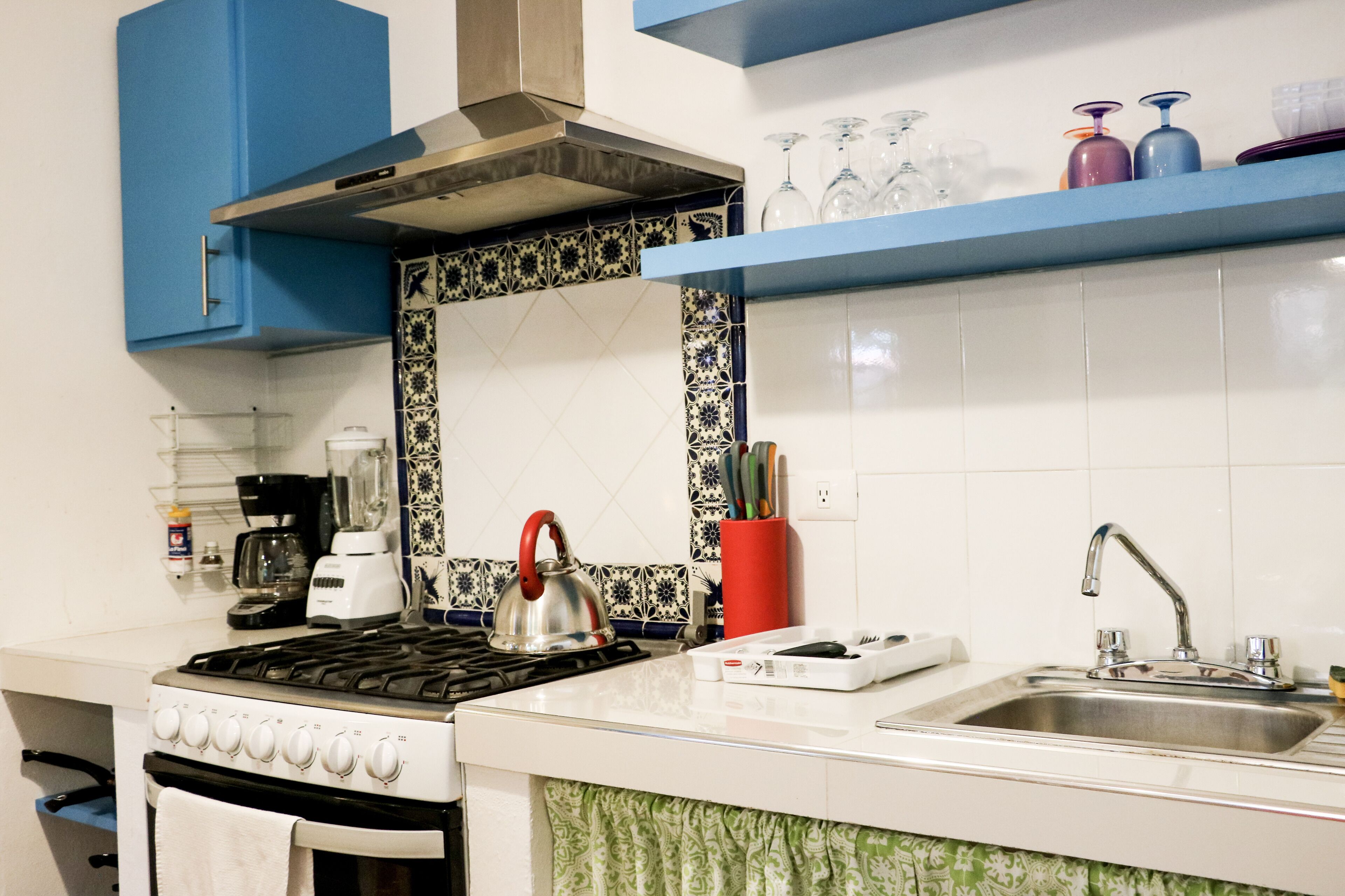 A kitchen with a stove, sink, and blue cabinets.