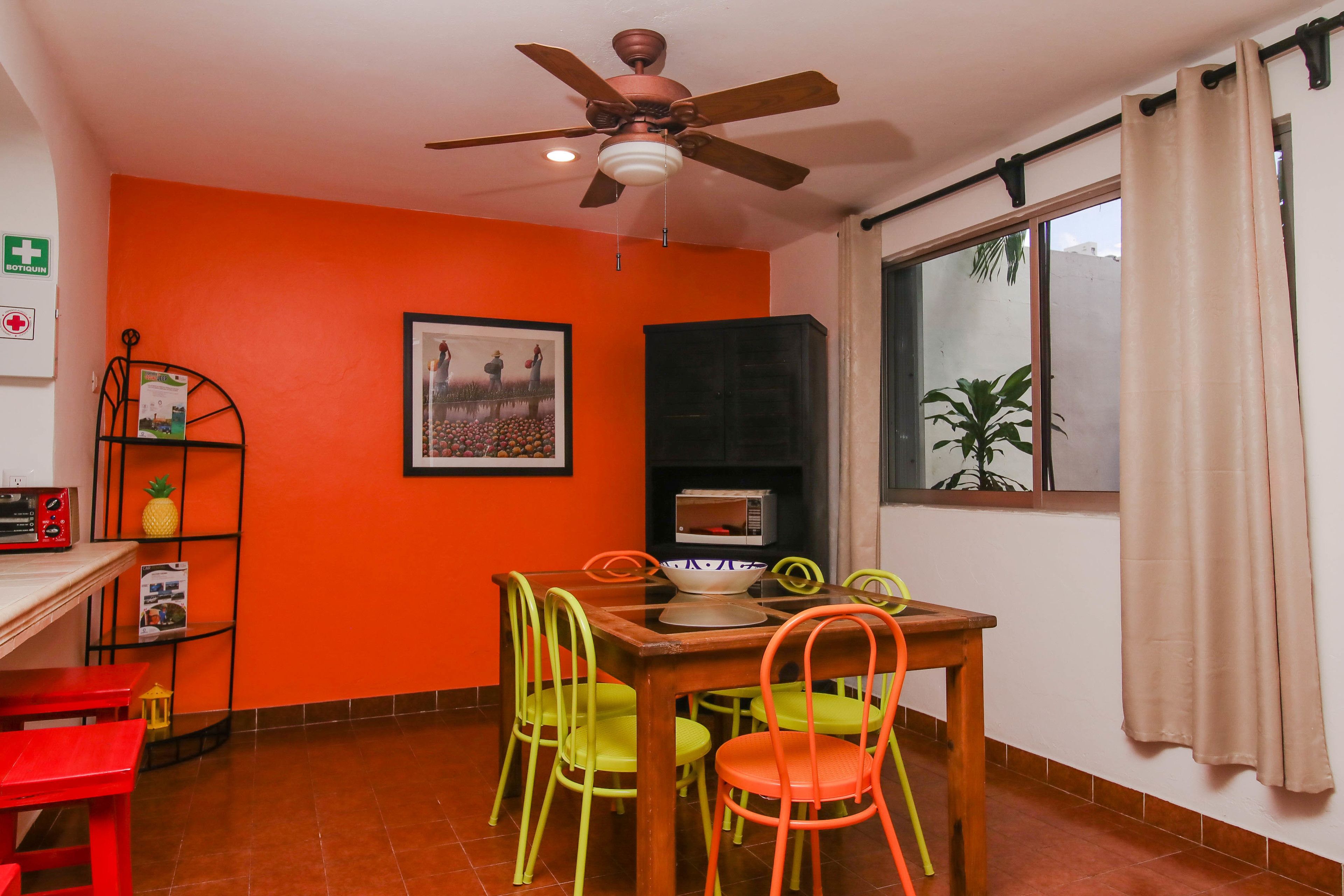 A dining area with a table, chairs, a ceiling fan, a microwave, and a framed picture on the wall.