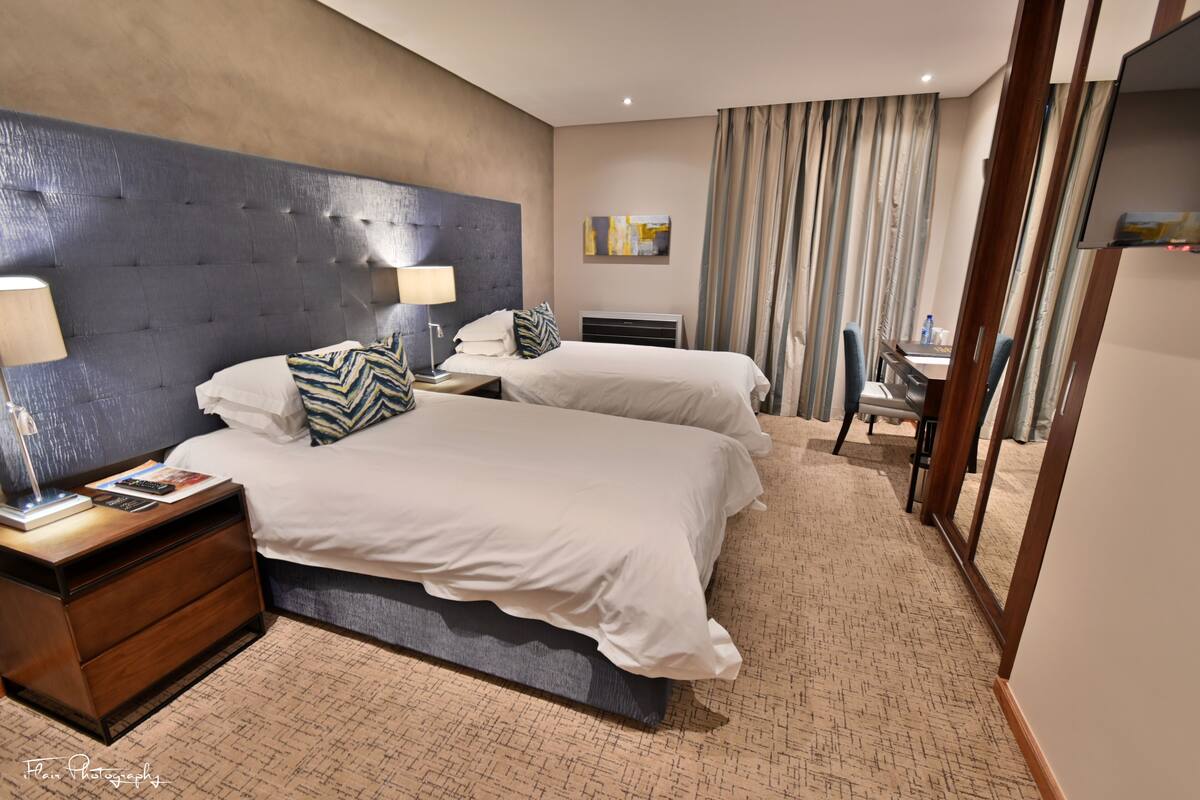 A hotel room with a large bed, a desk, a chair, and a TV.