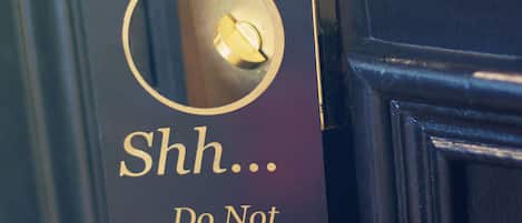 A door with a black door handle and a sign that reads "Shh... Do Not Disturb."