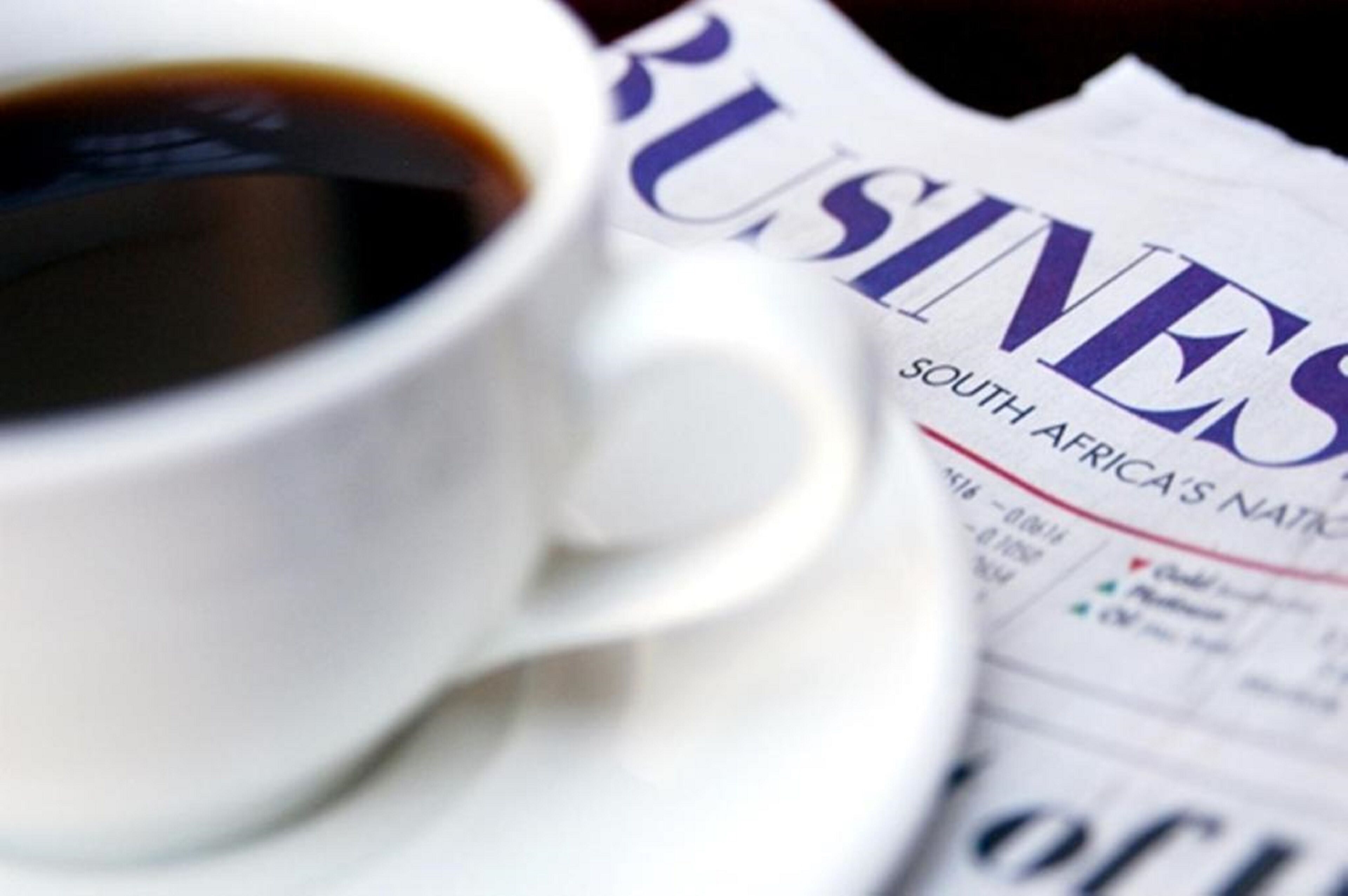 Une tasse de café et un journal intitulé « BUSINESS SOUTH AFRICA'S NATIONAL ».