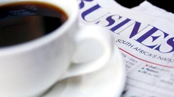 Une tasse de café et un journal intitulé « BUSINESS SOUTH AFRICA'S NATIONAL ».