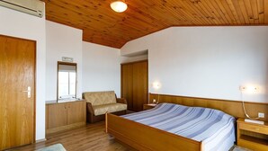 Ein Schlafzimmer mit einem hölzernen Bett, einem Nachttisch, einem Stuhl, einem Kleiderschrank und einem Spiegel.