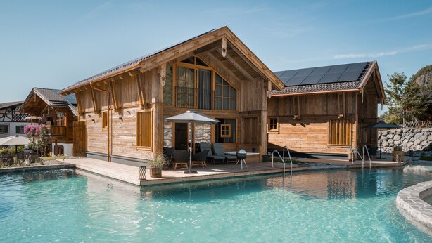 A wooden cabin with a pool, outdoor seating, and a stone wall. - Alpzitt - Chalets (Burgberg)