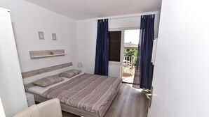 Une chambre à coucher avec un lit, une chaise, une petite table et une fenêtre avec des rideaux.
