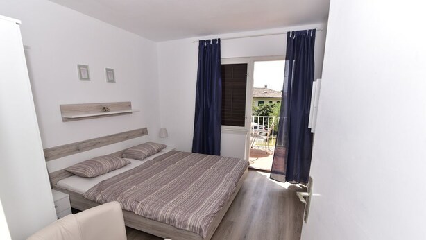Une chambre à coucher avec un lit, une chaise, une petite table et une fenêtre avec des rideaux.