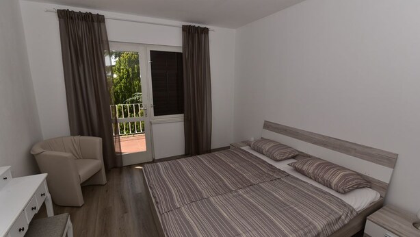 Une chambre à coucher avec un lit, une chaise, un bureau et une fenêtre avec des rideaux.