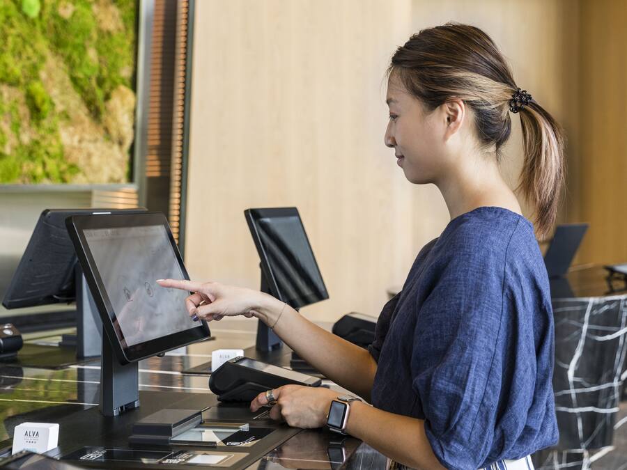Una dona interactua amb una quiosc digital al vestíbul d'un hotel.