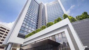 A modern high-rise building with multiple floors, large windows, and a flat roof with greenery. - Alva Hotel By Royal (Sha Tin)