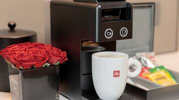 Una macchina per caffè con una tazza di caffè, una scatola di rose rosse e un vassoio con cialde per caffè.