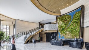 A spacious lobby with a curved staircase, a reception desk, and a large wall mural. - Alva Hotel By Royal (Sha Tin)
